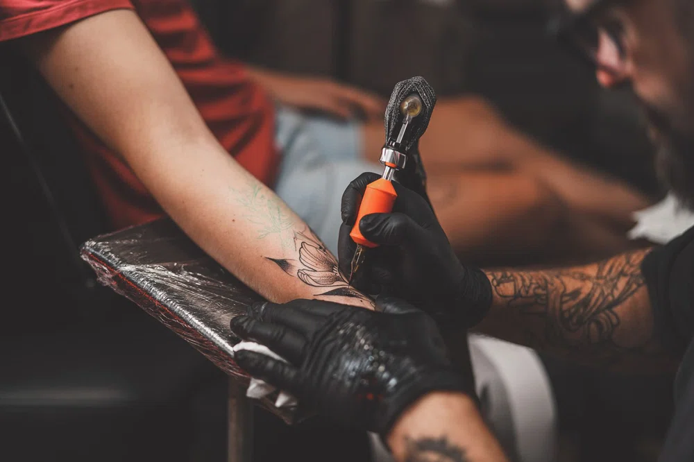 Maestro del tatuaje trabajando con su máquina de tatuar