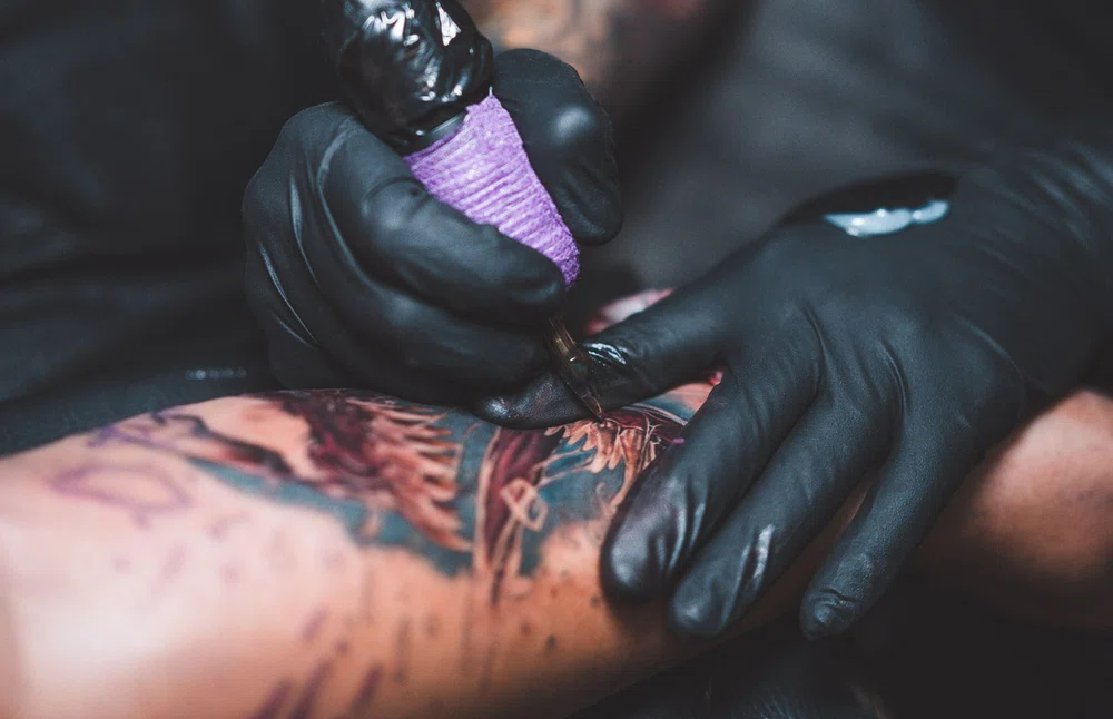 Artist tattooing in color on a client's skin