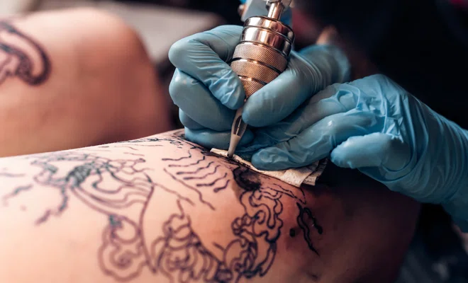 tatuador haciendo tatuaje a un cliente.