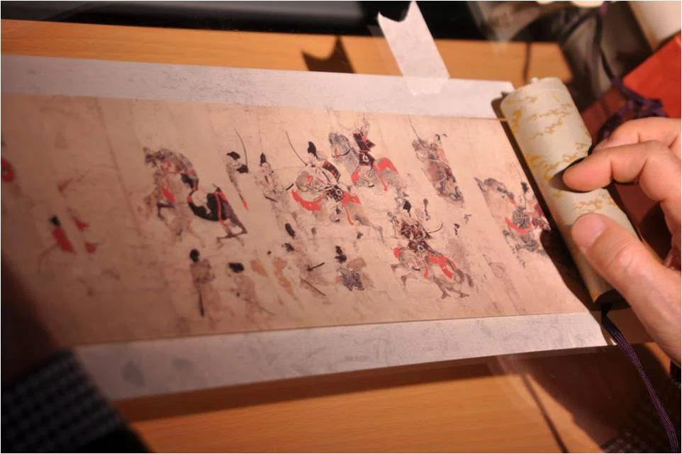 Emakimono manga on a paper scroll drawn in black and red ink depicting battles.