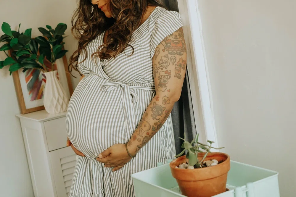 fotografía mujer embarazada muestra su brazo izquierdo tatuado