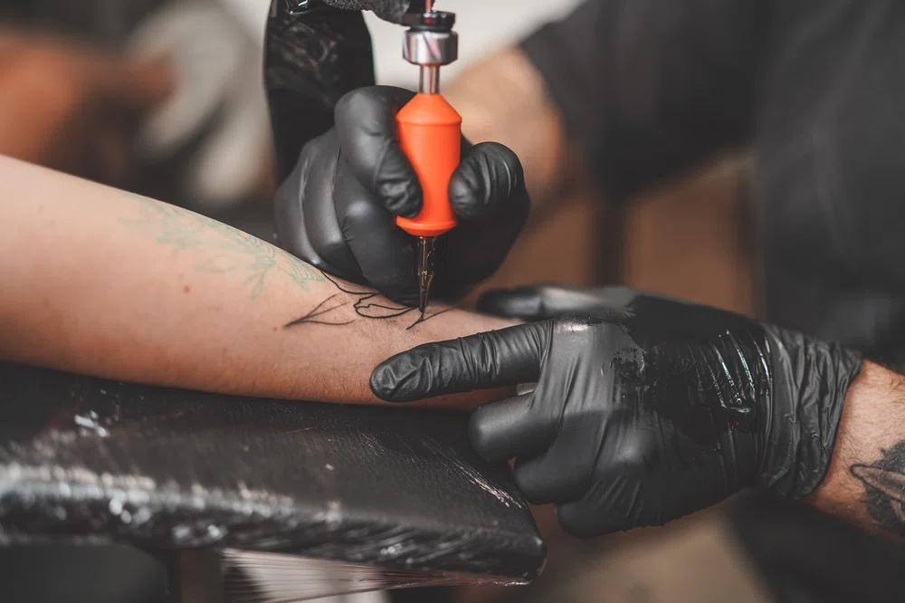 Realizando un tatuaje sobre un cliente. Cómo tatuar líneas perfectas
