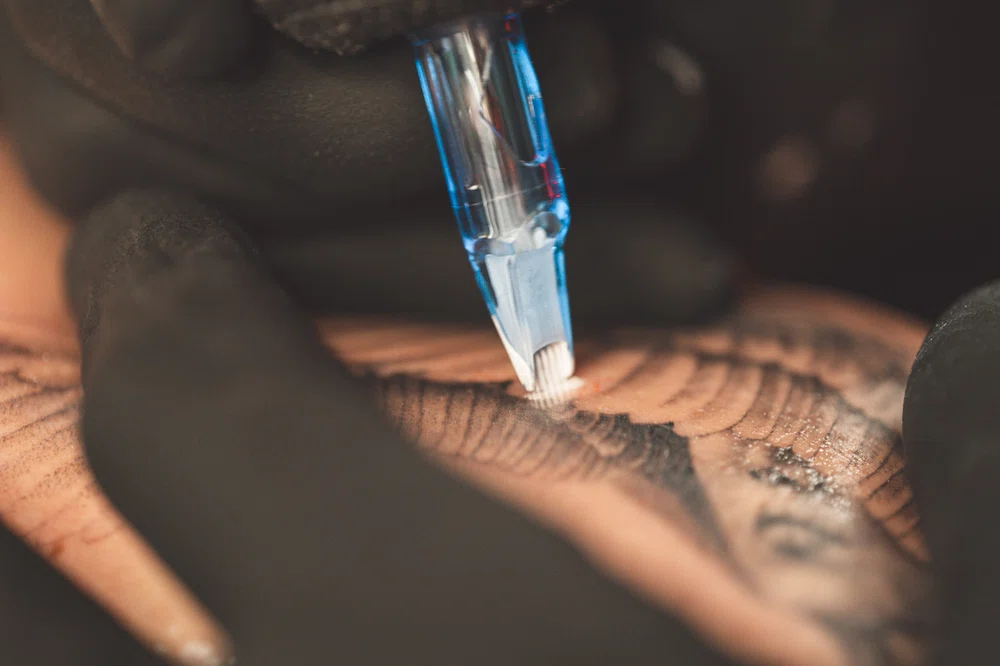 Utilizando agujas magnum de agrupación horizontal tatuando a un cliente