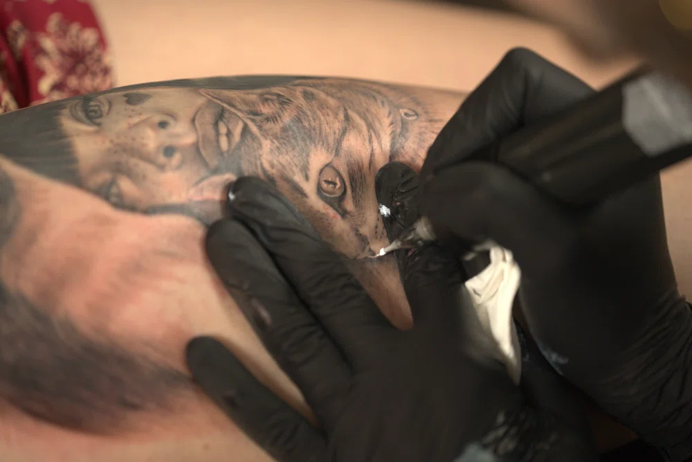 tattoo artist performing a black and gray tattoo on a client's skin