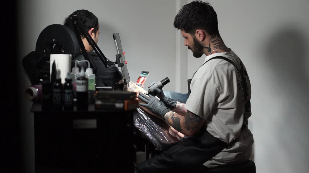 Coreh Lopez, tattoo artist, tattooing a client in his tattoo studio