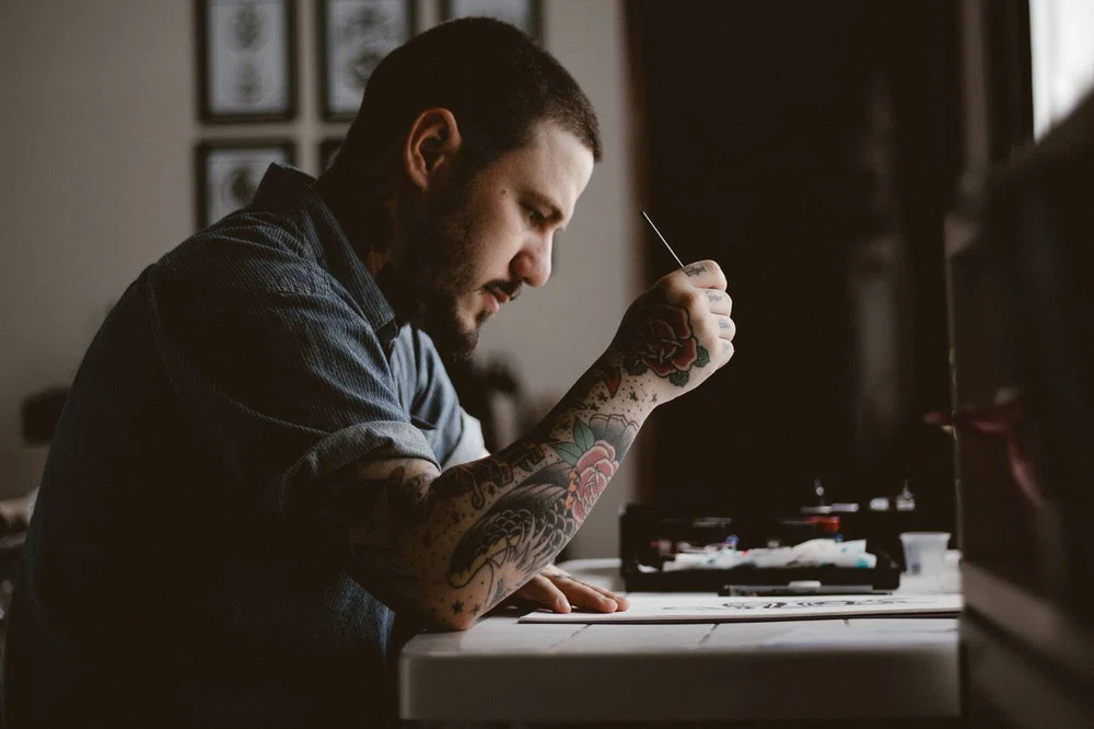 artista de tatuaje realizando un diseño de tatuaje sobre papel.