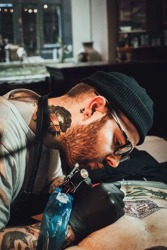 tatuador tatuando un diseño en el pecho de un hombre
