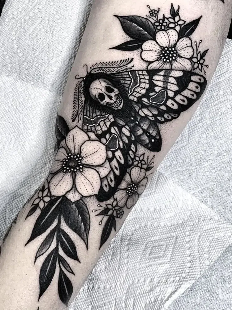 tatuaje de mariposa con calavera y flores en estilo blackwork