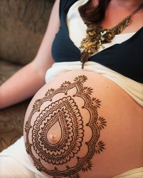 mujer embarazada con un tatuaje en el vientre realizado con henna.