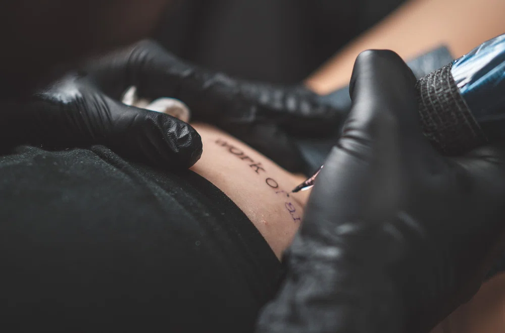 Tatuando letras en un cliente. Escoger la aguja adecuada para tatuar.