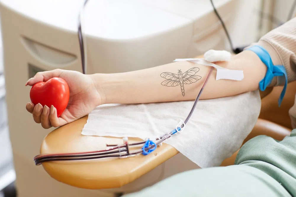 brazo tatuado de una mujer donando sangre