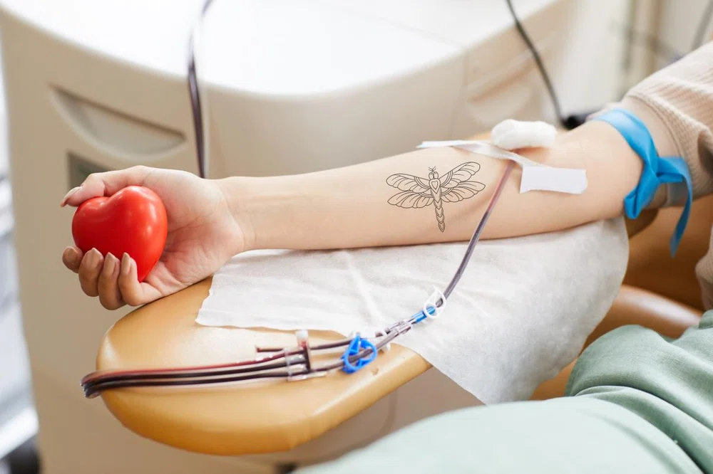 tattooed arm of a woman donating blood