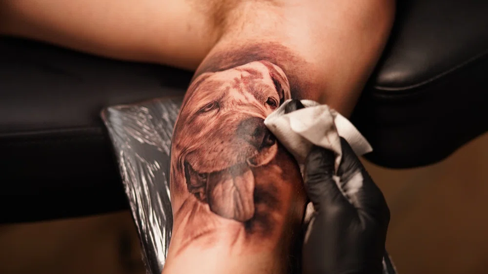 tatuando un perro en el brazo de un cliente. Tatuajes de mascotas