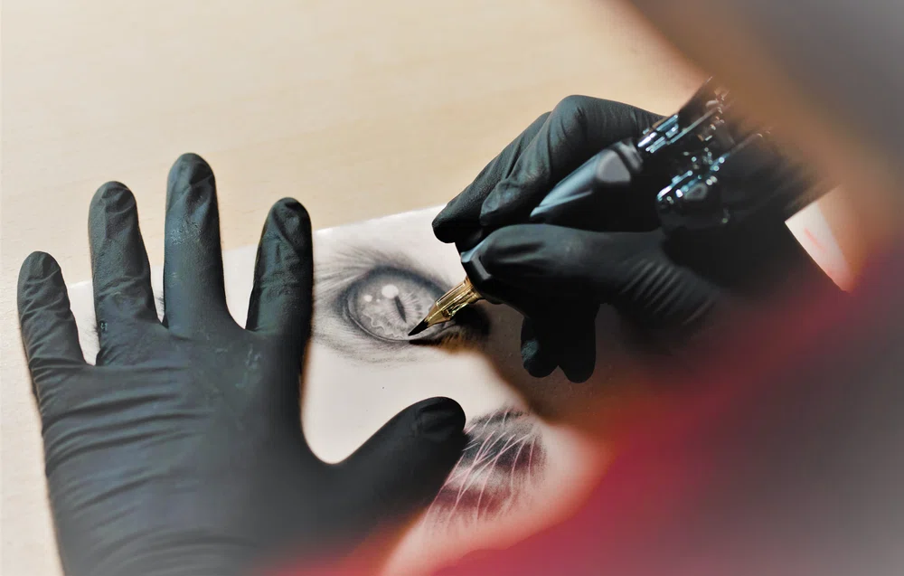 Artista del tatuaje practicando sobre piel sintética