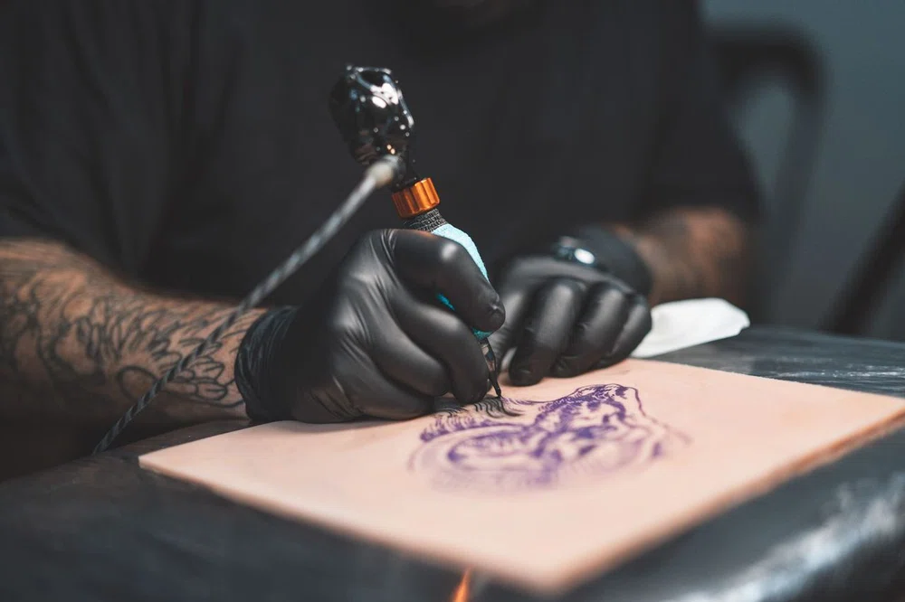 Professional tattooist tattooing on synthetic skin