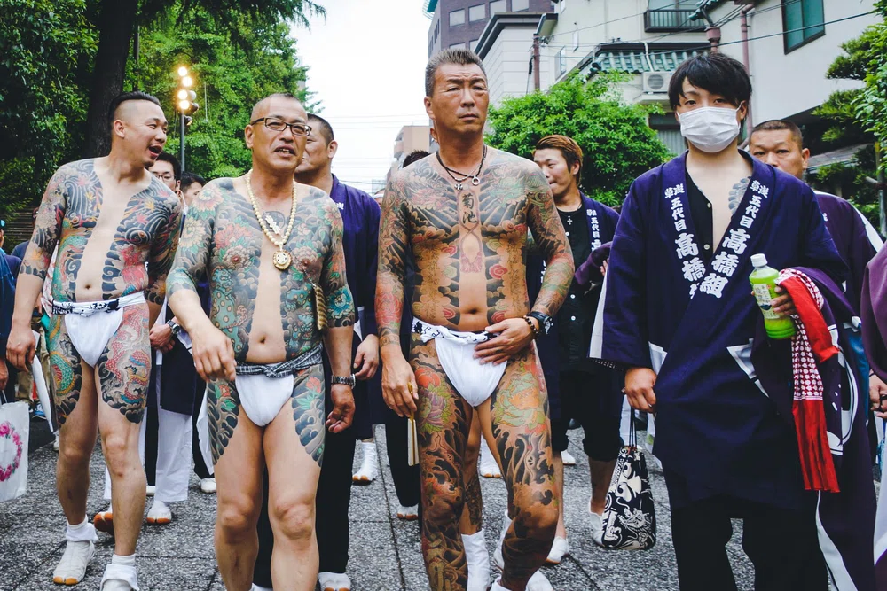 Grupo de hombres tatuados paseando por la calle en Japón. Cultura Yakuza y tatuajes